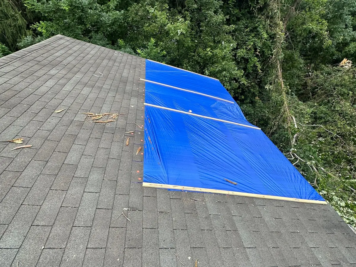 Wood battens fastening blue tarp strips flat against the shingles of the Columbia roof