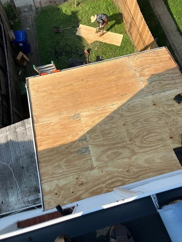 The same small rear low-slope roof re-decked in new plywood with white metal edge trim around the perimeter, seen from above