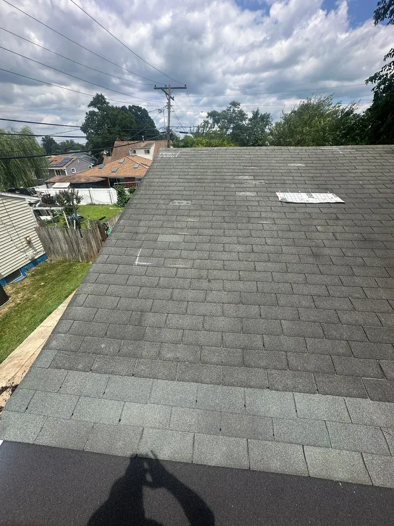 Aged gray three-tab shingle slope shot toward the eave, with chalk marks ringing damaged shingles
