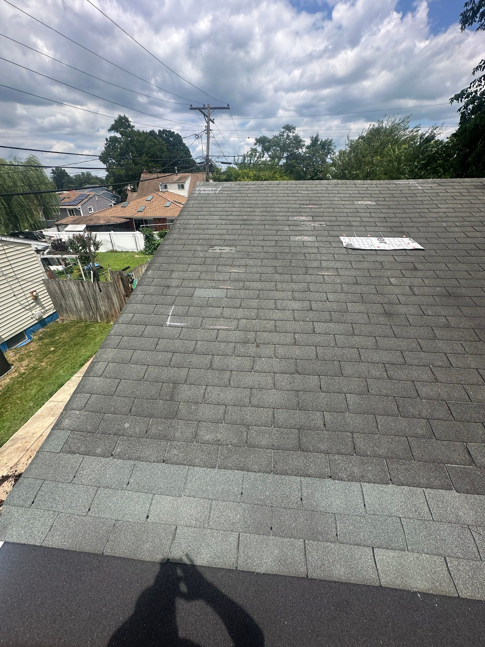 Aged gray three-tab shingle slope shot toward the eave, with white and pink chalk marks ringing damaged shingles