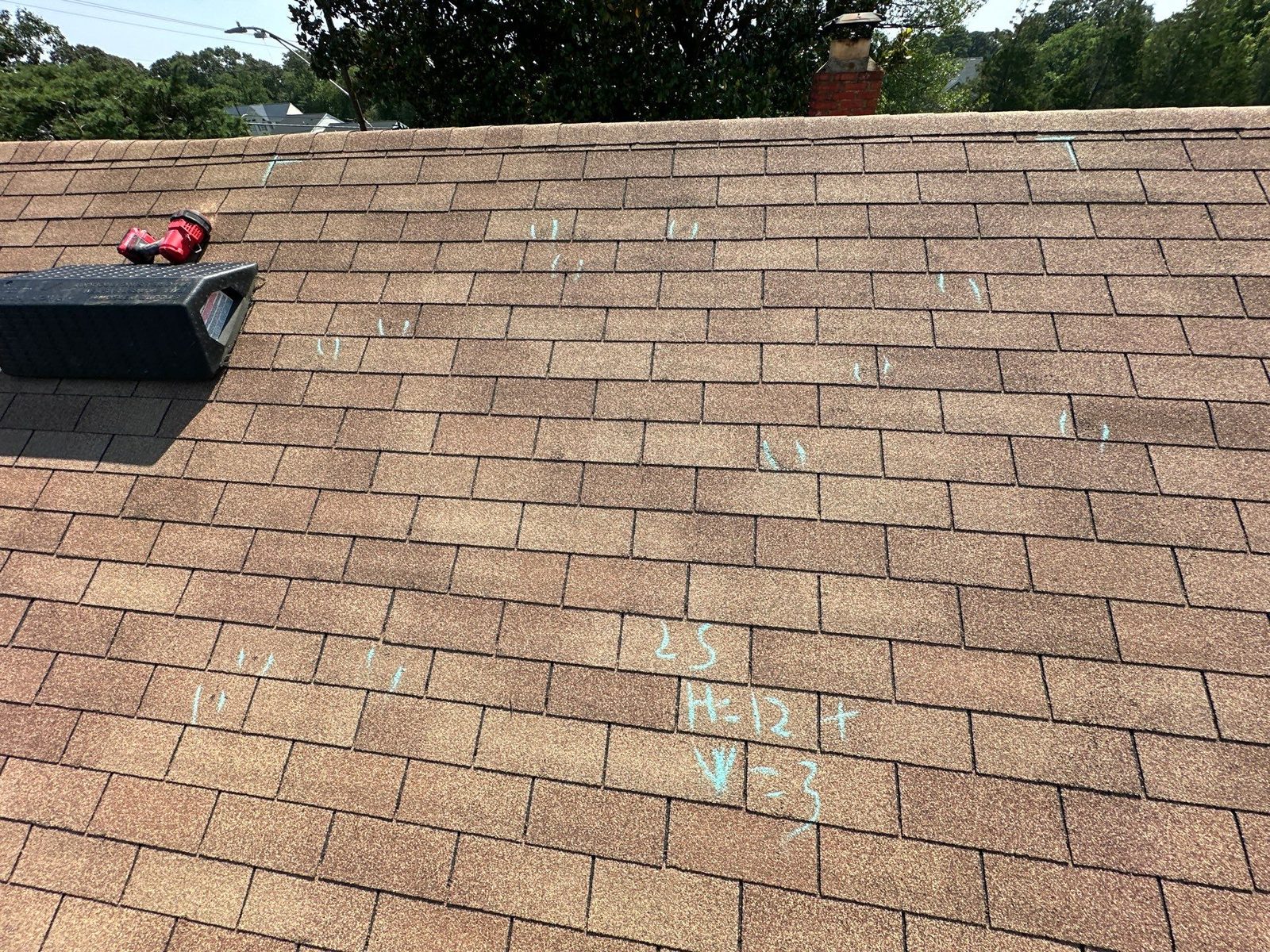 Hail hits circled in chalk on a tan shingle slope with the field measurements written beside them