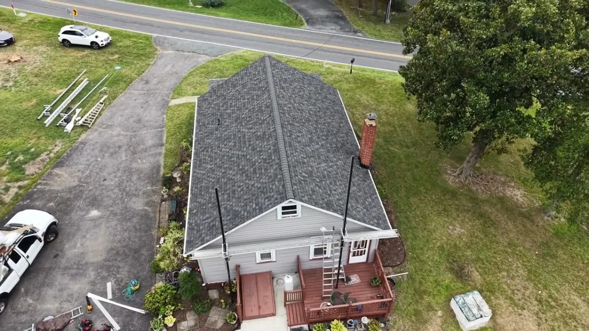 Aerial view of the same rear corner with the roof replacement complete, a full gray architectural shingle field