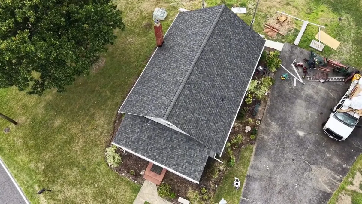 Straight-down aerial view of the cottage's completed gray architectural shingle roof, the full ridge and the hip lines
