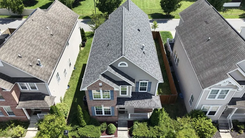 An aerial view of a two-storey Maryland home with a newly finished gray architectural shingle roof in a suburban neighborhood