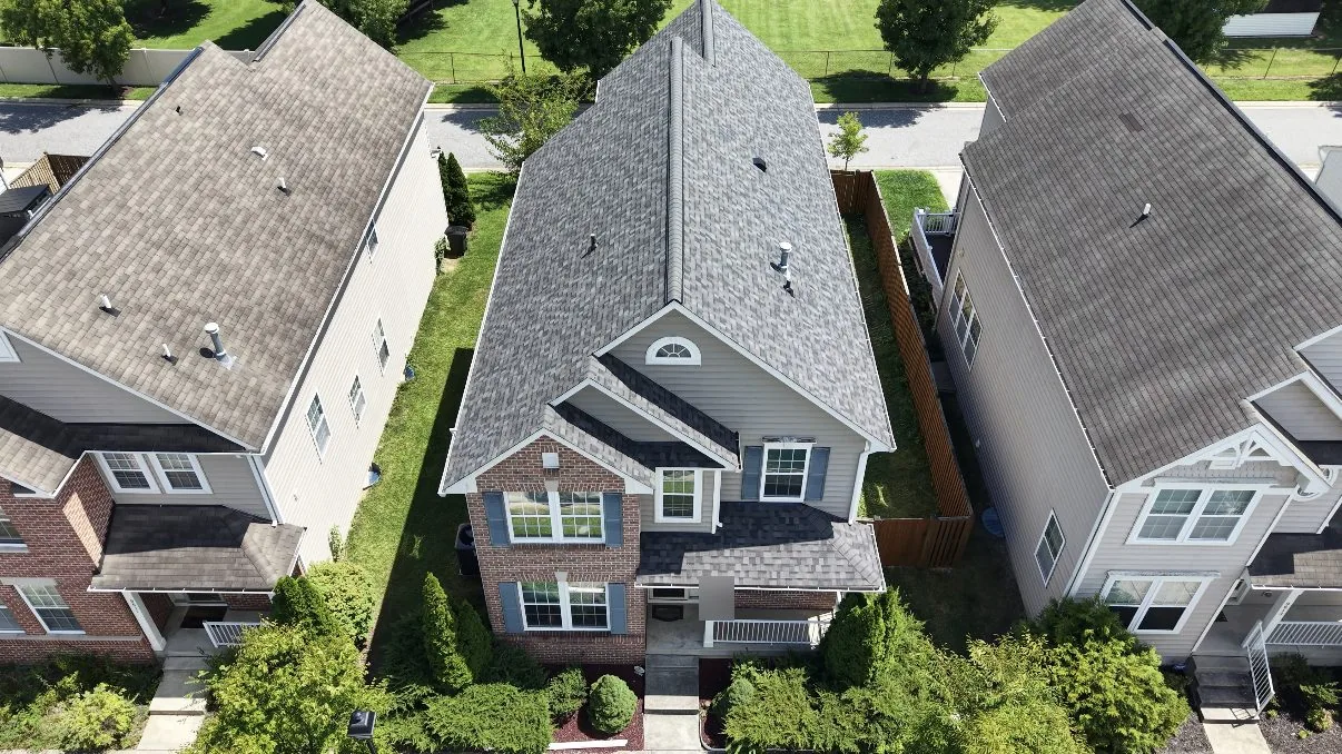 Aerial view over a two-storey brick and vinyl house with a newly finished gray architectural shingle roof
