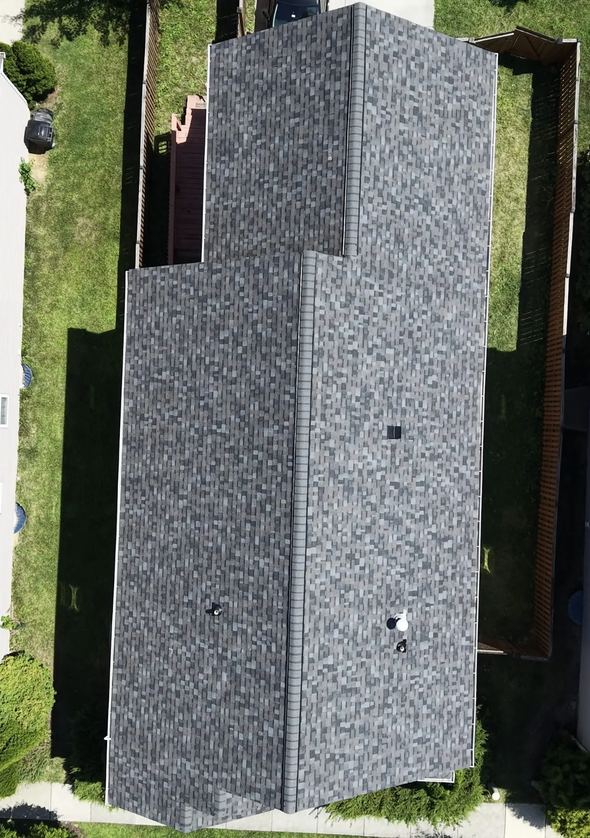 Straight-down aerial view of a completed gray architectural shingle roof across two intersecting gable planes