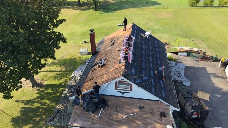 Drone view of a house mid-replacement, one slope stripped to plank decking and the other covered in dark underlayment