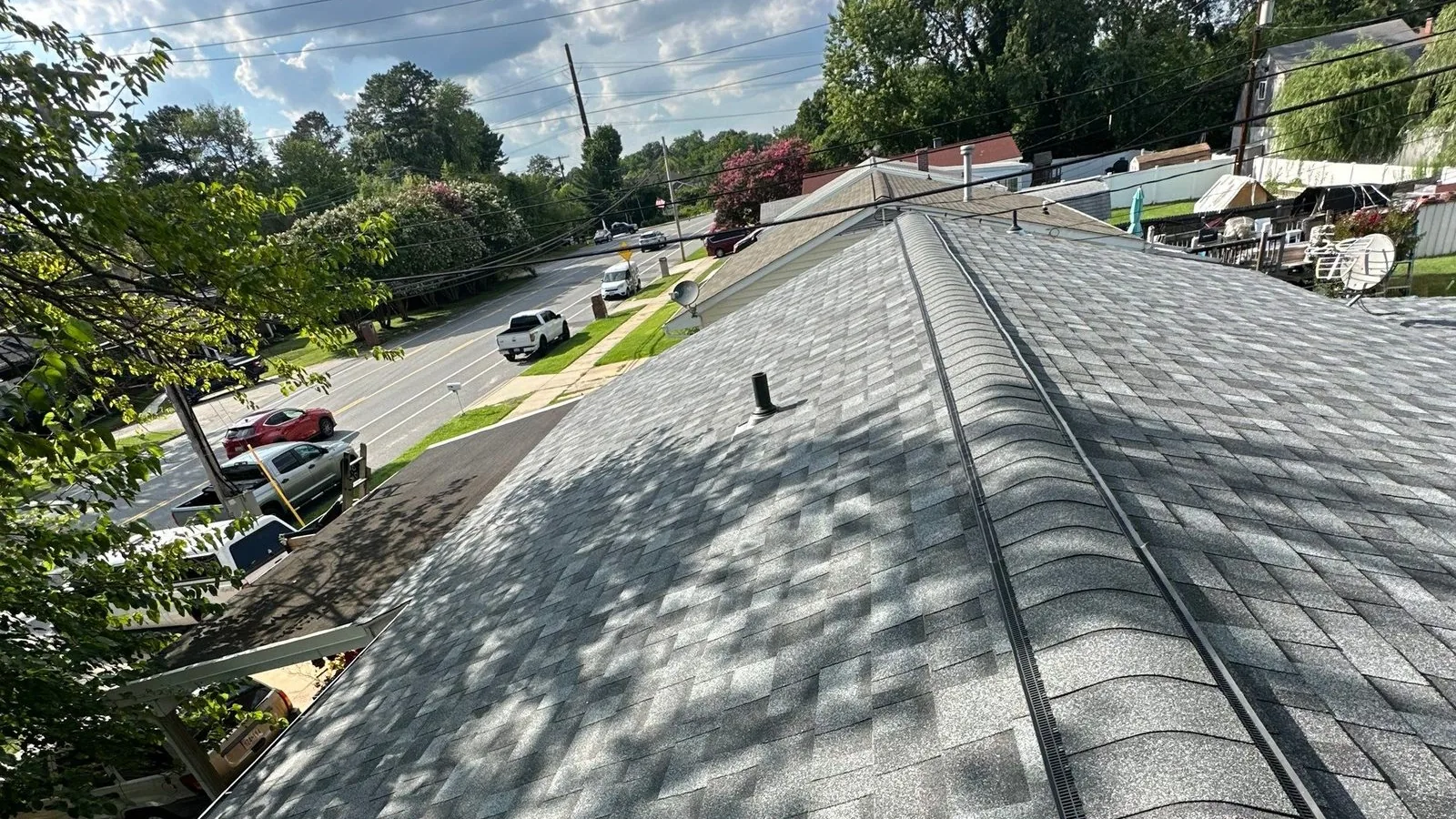Finished light-gray architectural shingle roof shot along the ridge, with a continuous black ridge vent strip