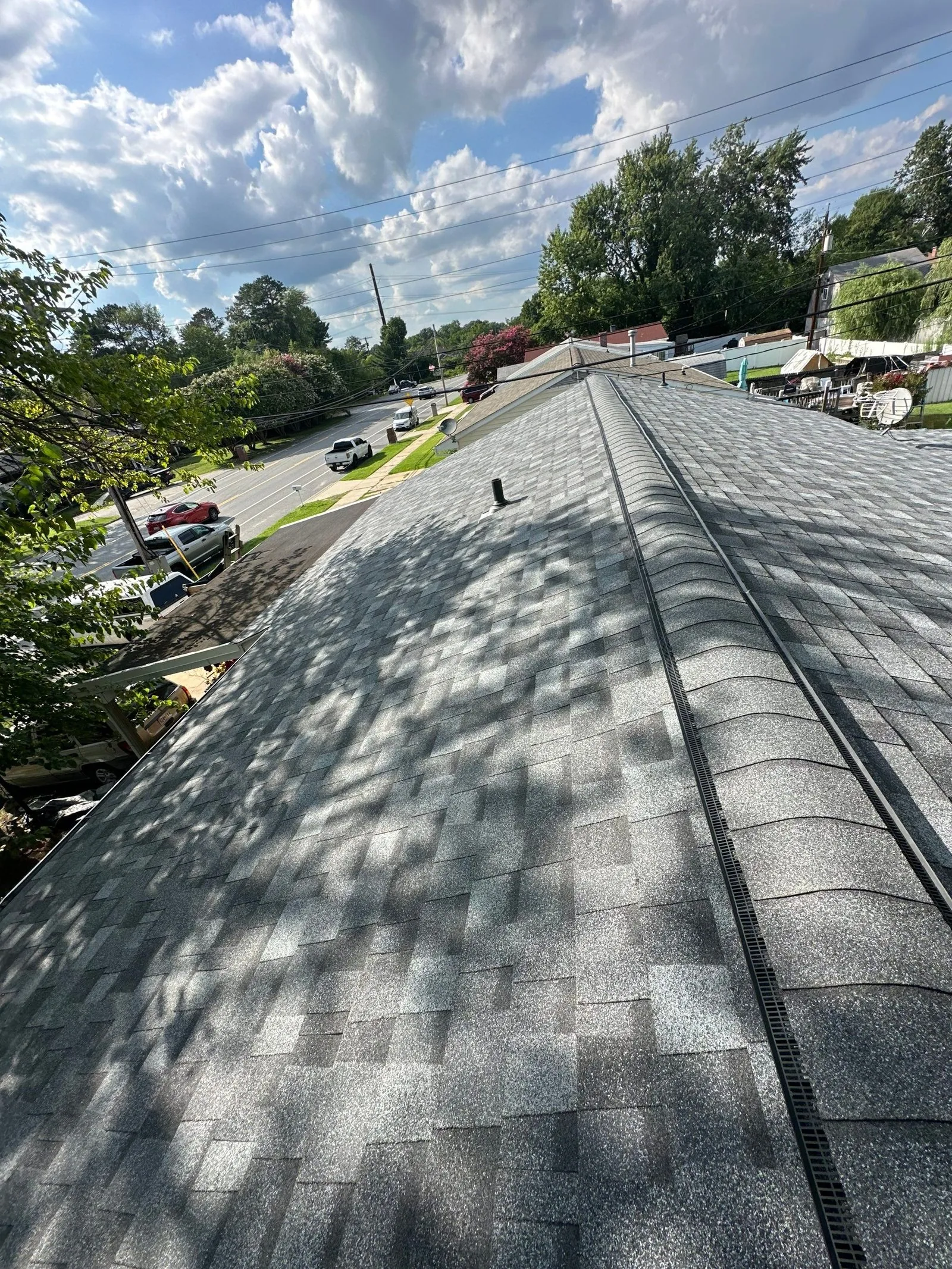 Finished light-gray architectural shingle roof shot along the ridge, with a continuous black ridge vent strip