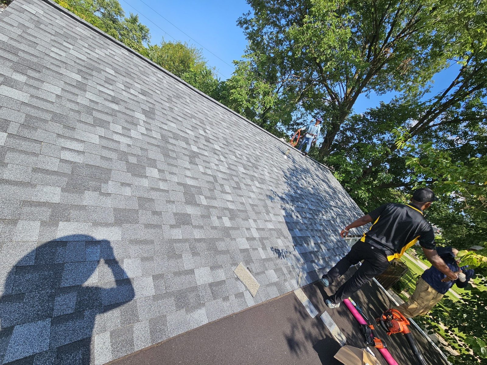 A freshly laid field of light-gray architectural shingles running up a large slope in warm evening light