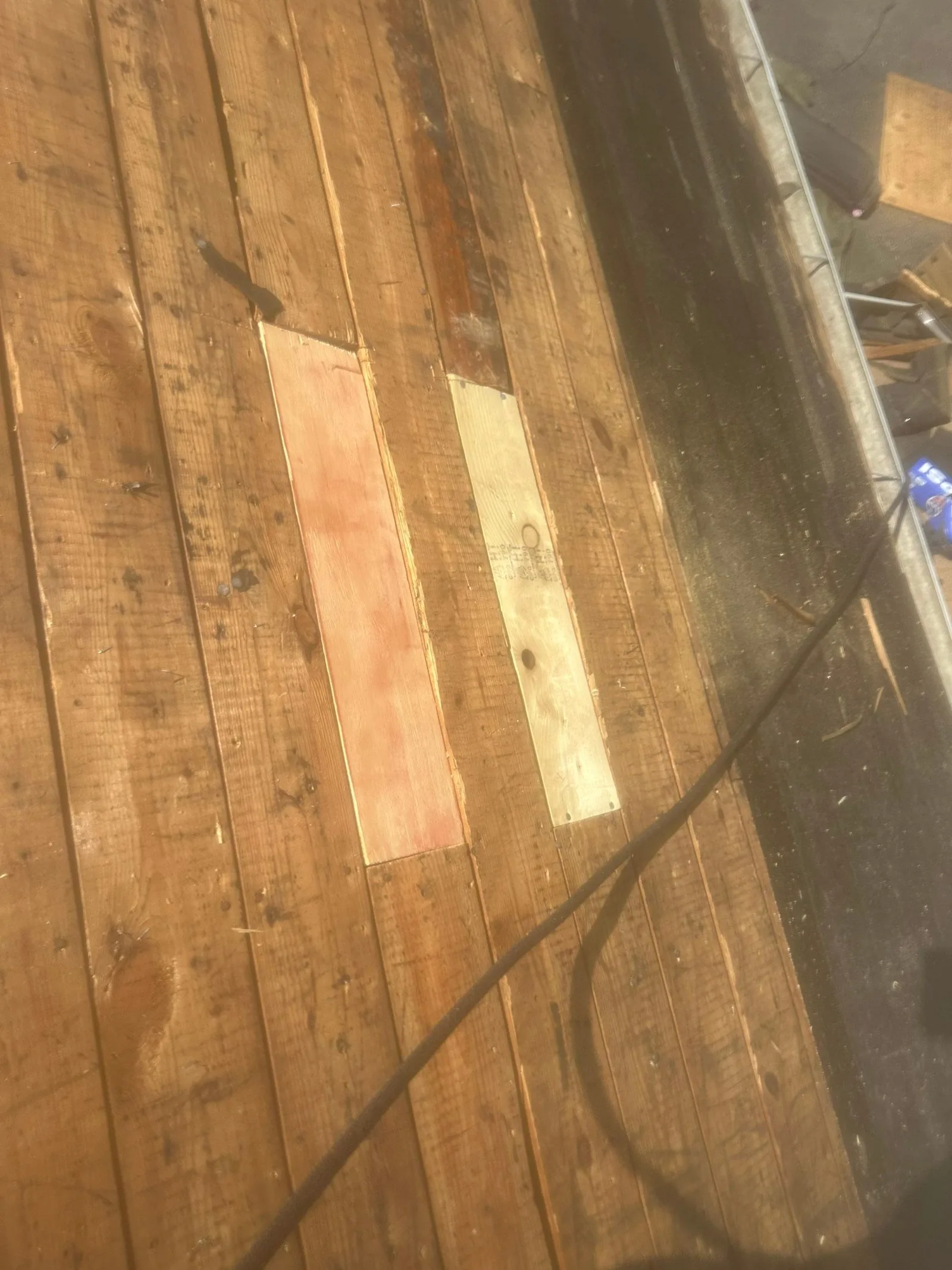 Two new let-in decking boards among the original planks in warm afternoon light