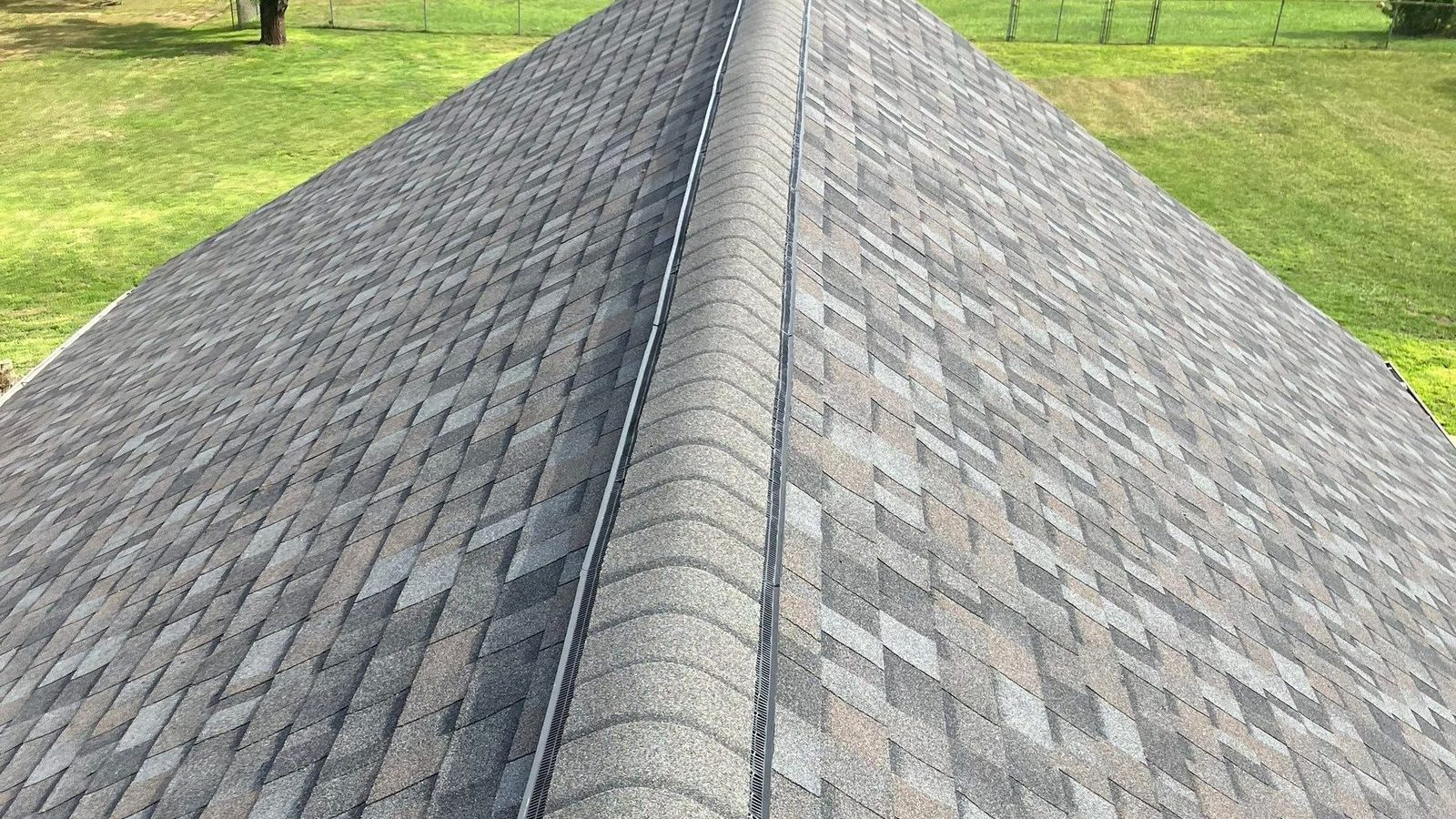 New ridge vent running the full length of a finished gray architectural shingle roof
