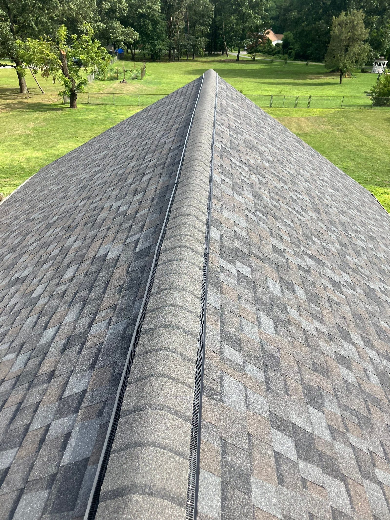 New ridge vent running the full length of a finished gray architectural shingle roof