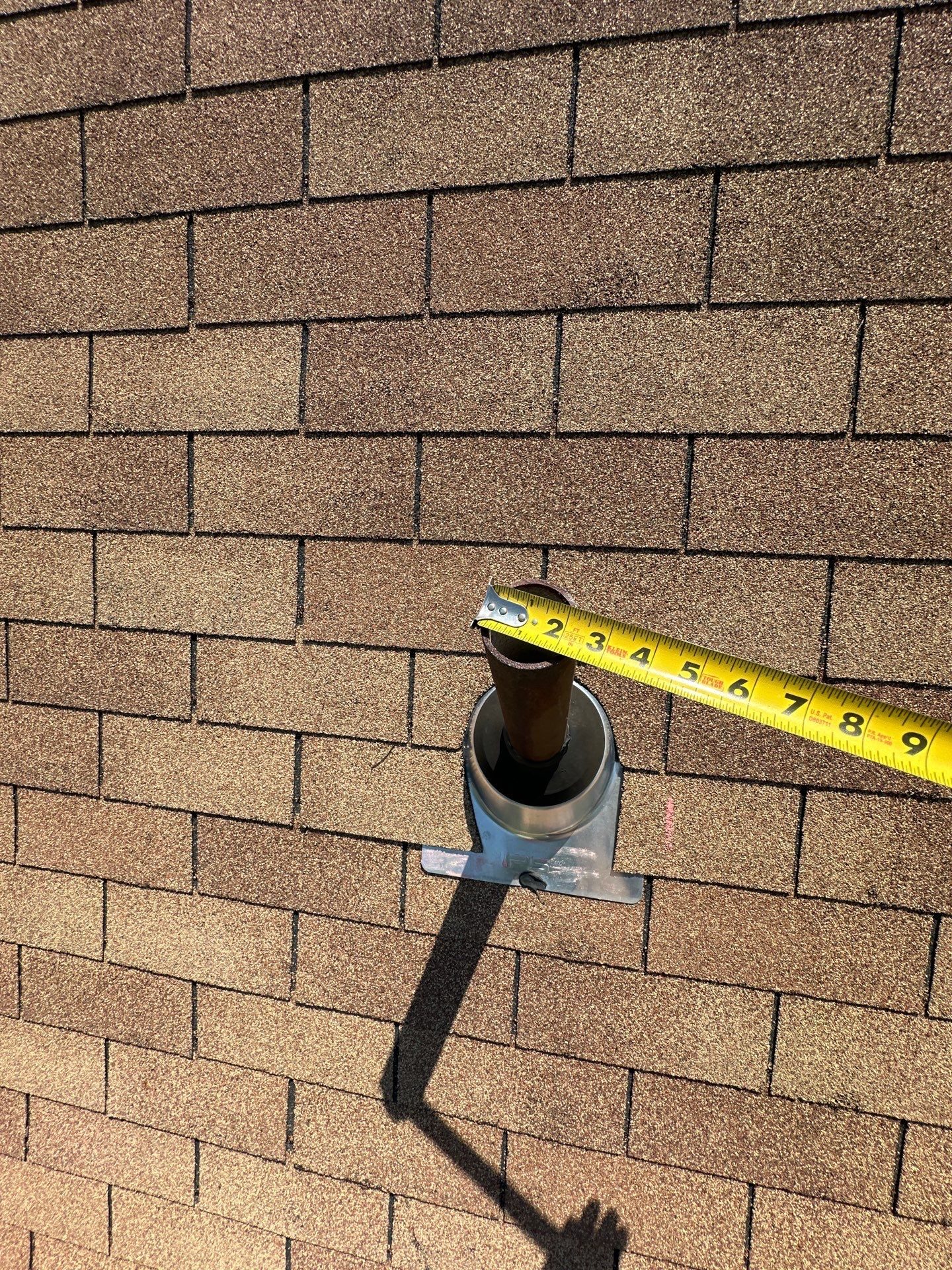 Metal plumbing vent pipe through the old tan shingle roof, measured with a tape before replacement