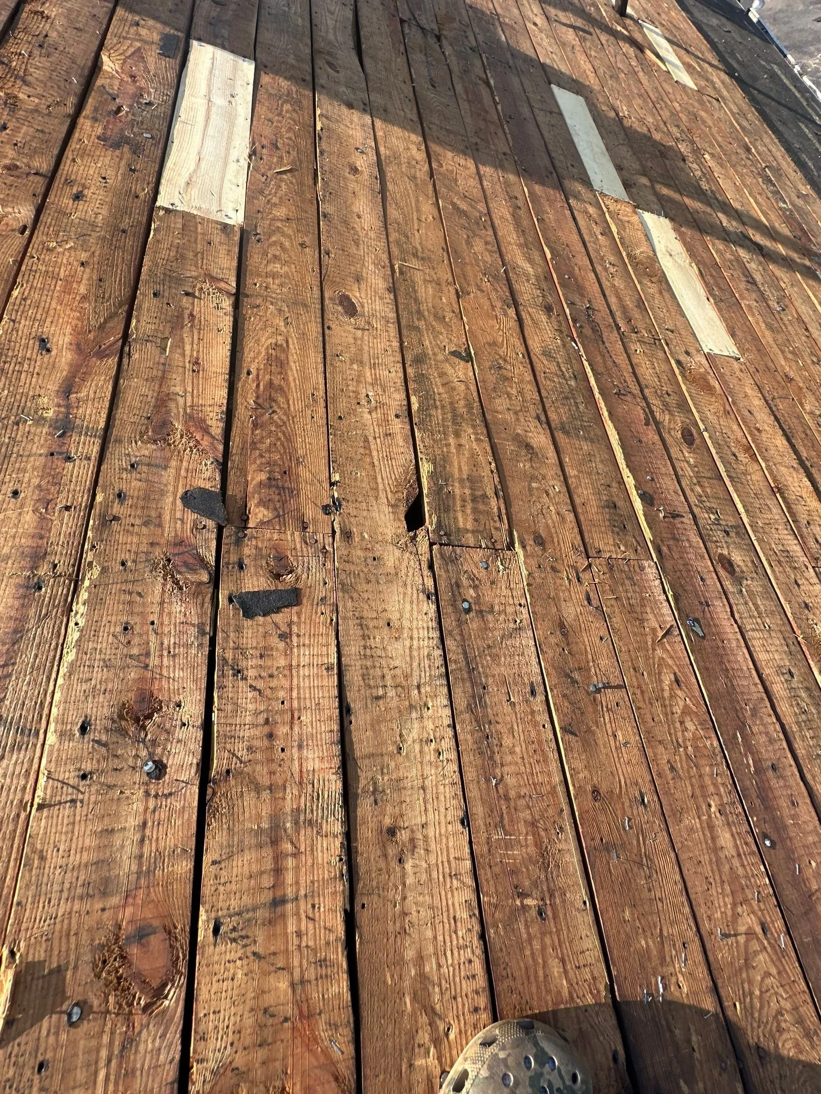 Several new let-in replacement boards across a stripped plank roof deck