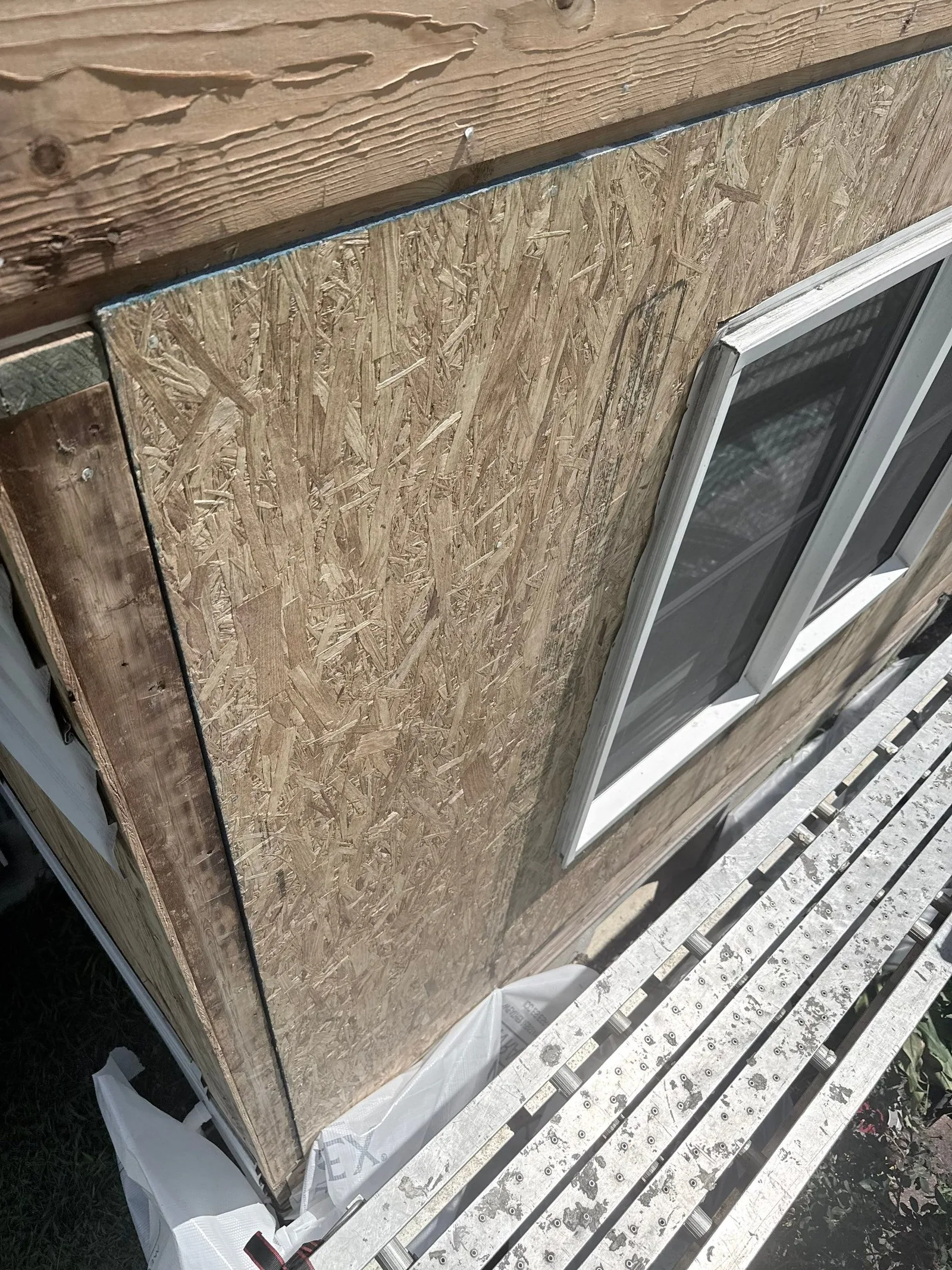 New OSB sheathing fitted around a window beneath the open eave