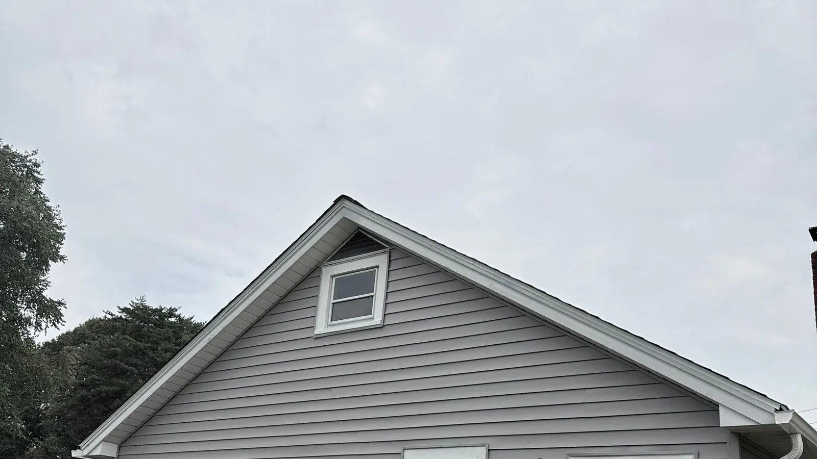 Rear elevation finished in new gray siding, with the wood deck and railing alongside