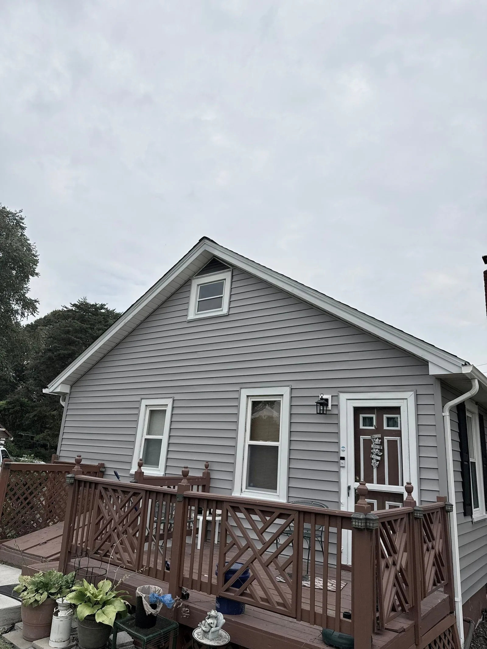 Rear elevation finished in new gray siding, with the wood deck and railing alongside