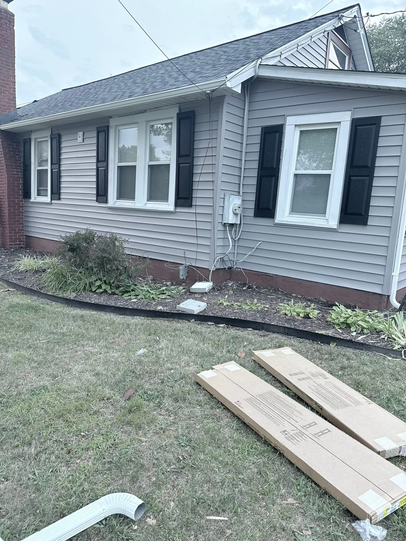 Side elevation finished in new gray siding with the remaining trim stock still on the lawn