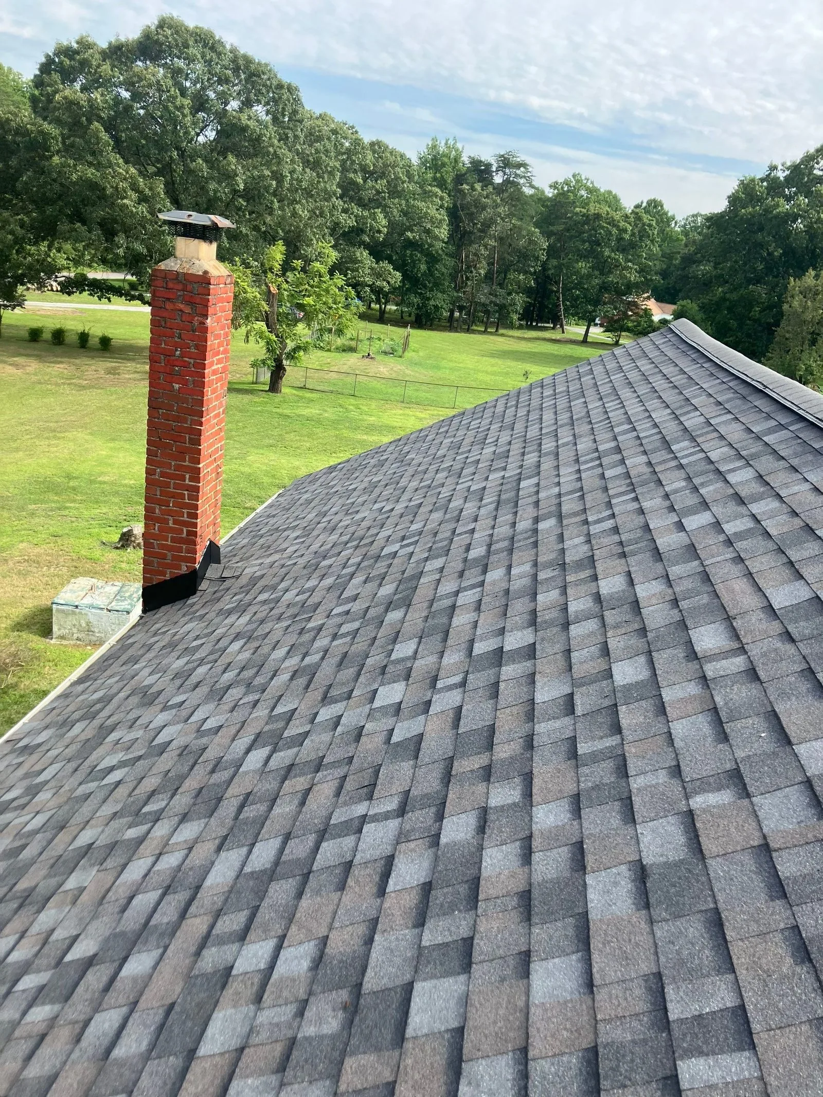Finished architectural shingle roof with new base flashing at the brick chimney